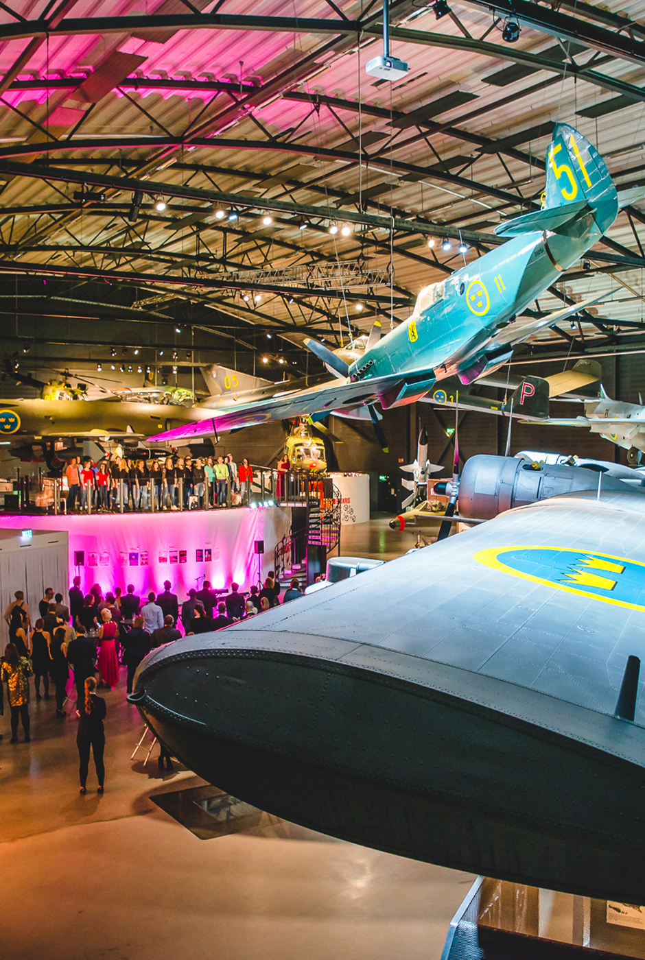 En stor folksamling st&aring;r nedanf&ouml;r ett av planen som h&auml;nger fr&aring;n taket i en av utst&auml;llningshallarna.