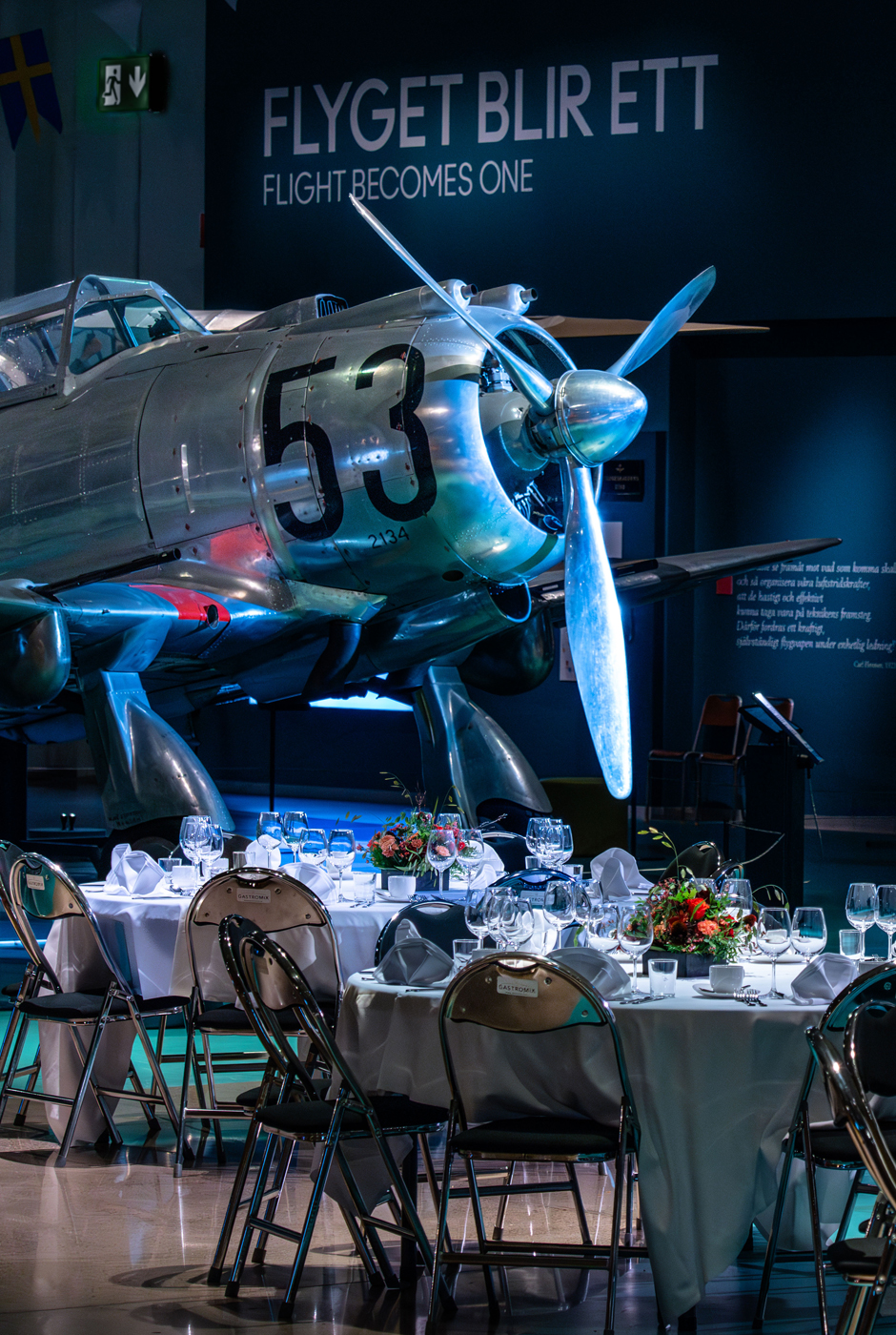 Dukade bord med vita dukar st&aring;r uppst&auml;llda bland flygplanen i en av utst&auml;llningshallarna.